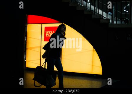 I viaggiatori camminano oltre il logo Wells Fargo a Penn Station, New York City, USA. Foto Stock