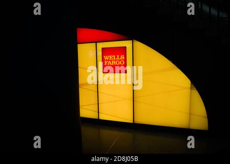 I viaggiatori camminano oltre il logo Wells Fargo a Penn Station, New York City, USA. Foto Stock