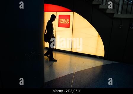 I viaggiatori camminano oltre il logo Wells Fargo a Penn Station, New York City, USA. Foto Stock