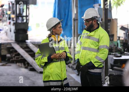 Uomini e donne in fabbrica che utilizzano la macchina in officina. Foto Stock