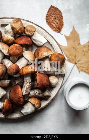 Vassoio di legno con funghi forestali, foglie secche d'autunno e una candela. Foto Stock