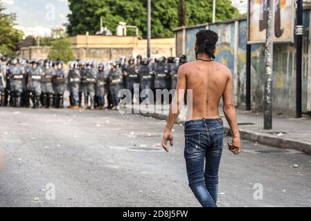 Beirut, Libano, 30 ottobre 2020. Avvicinandosi alla linea di polizia con una pietra da gettare come un piccolo gruppo di uomini da Tripoli e Beirut scontro con le forze libanesi di sicurezza interna. Scuffi sono scoppiati durante un tentativo del gruppo panislamico Hizb Ut Tahrir di marciare all'ambasciata francese per protestare contro ciò che essi hanno visto come la posizione anti-islamica del presidente Emmanuel Macron. Le emozioni hanno corso alto come è stato sentito il profeta Maometto è stato disrispettato durante il suo mese di compleanno. Credit: Elizabeth Fitt/Alamy Live News Foto Stock