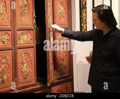 (201030) -- DONGYANG, 30 ottobre 2020 (Xinhua) -- Chen Guohua, un maestro di livello provinciale di arti e artigianato, presenta un pezzo della sua collezione di sculture in legno presso il suo studio a Dongyang, nella provincia di Zhejiang della Cina orientale, 20 ottobre 2020. La scultura in legno Dongyang, originaria della città di Dongyang, nella provincia di Zhejiang, ha una storia di oltre mille anni dalla dinastia Tang (618-907 d.C.). E' uno dei rappresentanti di spicco dell'arte popolare cinese dell'intaglio, basato su rilievi aerei, l'intaglio del legno Dongyang ha formato le sue caratteristiche distintive con strati ricchi e lucentezza leggera. Esso Foto Stock