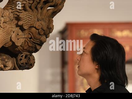 (201030) -- DONGYANG, 30 ottobre 2020 (Xinhua) -- Chen Guohua, un maestro di livello provinciale di arti e artigianato, esamina i dettagli di un pezzo della sua collezione di sculture in legno presso il suo studio a Dongyang, nella provincia di Zhejiang nella Cina orientale, 20 ottobre 2020. La scultura in legno Dongyang, originaria della città di Dongyang, nella provincia di Zhejiang, ha una storia di oltre mille anni dalla dinastia Tang (618-907 d.C.). E' uno dei rappresentanti di spicco dell'arte popolare cinese dell'intaglio, basato su rilievi aerei, l'intaglio del legno Dongyang ha formato le sue caratteristiche distintive con ricchi strati e ligh Foto Stock