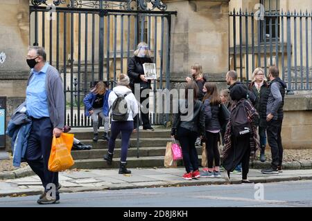 Oxford, Oxfordshire, Regno Unito - Venerdì 30 Ottobre 2020 - i visitatori del centro di Oxford ascoltano una guida turistica fuori dalla Bodleian Library mentre Oxford si prepara ad entrare nelle restrizioni del Covid Tier 2 domani sabato 31 Ottobre. Photo Steven May / Alamy Live News Foto Stock