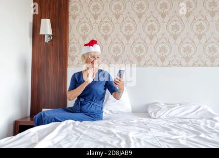 Natale, x-mas, online Store Concept - una donna in un cappello Babbo Natale helper con uno smartphone. Foto Stock