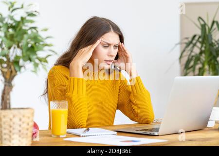 Donna massaggiante templi di testa a causa di mal di testa da lungo lavoro Foto Stock