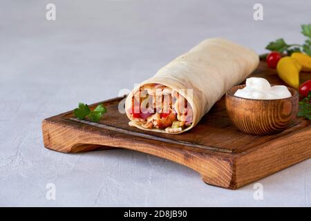 Shawarma con pollo e salsa all'aglio su tavola di legno. Primo piano Foto Stock