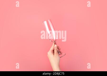 Tenere a mano un bicchiere di champagne su sfondo rosa. Foto Stock