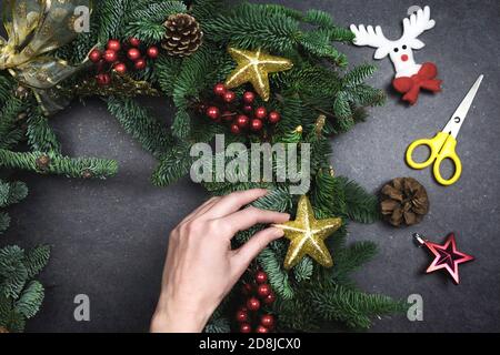 fare la corona di natale con rami di abete e decorazioni. Sfondo nero Foto Stock