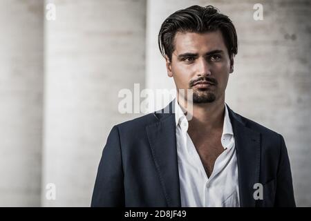 Ritratto di giovane con stile alla moda. Capelli e pizzetto alla moda. Indossa una camicia bianca e una giacca. Foto Stock