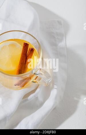 Bevande calde Toddy cocktail con limone, miele e cannella bastone in vetro su sfondo bianco. Bevanda invernale speziata Foto Stock