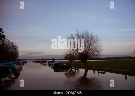 Un'immagine paesaggistica con un canale sul Tamigi, vicino a Port Meadow, Oxford. Le barche e le case delle barche sono allineate su ogni lato del canale. Foto Stock