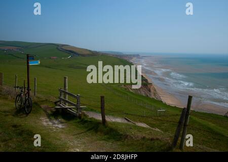 Vista panoramica sulla costa dell'Isola di Wight con l'oceano, una spiaggia stretta ai piedi delle scogliere. Un prato verde è sulla cima delle scogliere con strada Foto Stock