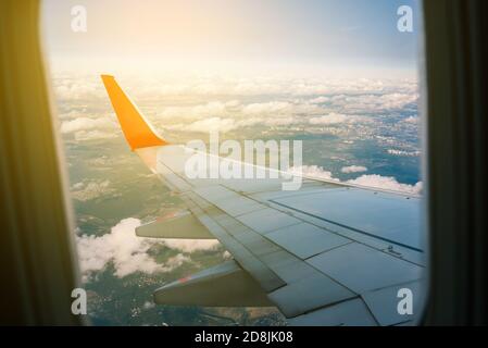 Vista di un'ala dell'aeroplano dalla finestra sulla città. Volo su un aereo passeggeri. Nuvole e cielo all'esterno della finestra del liner. Viaggi e turismo Foto Stock