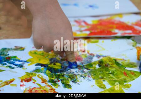 un bambino disegna. il disegno di un bambino inchiostri, vernice delle dita, le stampe a mano con il suo dito su carta bianca Foto Stock