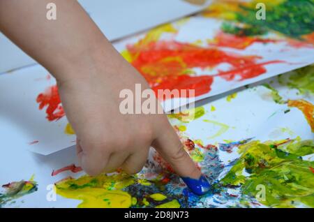 un bambino disegna. il disegno di un bambino inchiostri, vernice delle dita, le stampe a mano con il suo dito su carta bianca Foto Stock