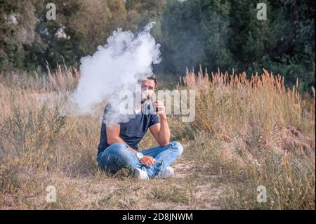 Elegante vape man che espala vapore dalla sigaretta elettronica. Concetto elettronico di sigaretta. Foto Stock