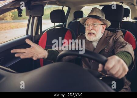 Ritratto della sua bella esperienza pazzo infastidito furioso uomo dai capelli grigi che guida l'auto in ingorgo che tiene il volante urlare Foto Stock