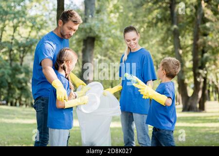 famiglia di volontari che raccolgono rifiuti di plastica in sacchetti riciclati, concetto di ecologia Foto Stock