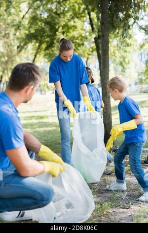 famiglia di attivisti che raccolgono rifiuti in sacchetti di plastica riciclati, concetto di ecologia Foto Stock