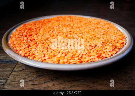 Una ciotola di lenticchie rosse su una superficie di legno con una profondità di campo poco profonda Foto Stock