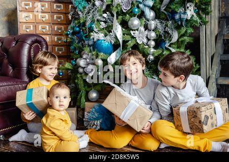 Felici i fratelli bambini che aprono i regali davanti all'albero di Natale. Tempo di Natale. Concentratevi sul bambino. Foto Stock