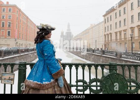 SAN PIETROBURGO, RUSSIA - 19 marzo 2018 - Vista posteriore dell'attore in costume di Caterina II in posa sul ponte durante una nevicata, guardando a parte, Chiesa di Foto Stock