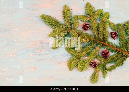 Posa piatta di rami di albero di Natale con coni su un sfondo blu chiaro Foto Stock