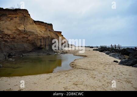 Le scogliere di Happisburgh Beach che mostrano erosione costiera, Norfolk, Regno Unito. Grandi massi sono stati collocati lungo la spiaggia per rallentare ulteriori danni. Foto Stock