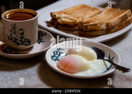 Mezza uova bollite, caffè, pane tostato, popolare colazione in stile cinese in Malesia Foto Stock