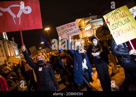 Varsavia, Polonia. 30 Ott 2020. Durante la protesta, i manifestanti che indossano maschere facciali tengono dei cartelli.decine di migliaia di persone sono scese per le strade della Polonia per una nona giornata di proteste contro una sentenza della Corte costituzionale che avrebbe imposto un divieto quasi totale dell'aborto in Polonia. I manifestanti guidati dai leader dell'organizzazione Strajk Kobiet (Women's Strike) hanno marciato dal centro di Varsavia al leader del partito al governo PIS (Legge e Giustizia), la casa di Jaroslaw Kaczynski. Credit: SOPA Images Limited/Alamy Live News Foto Stock