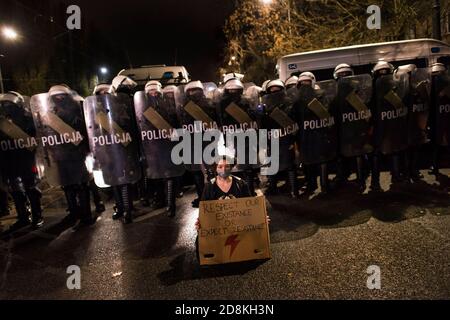 Varsavia, Polonia. 30 Ott 2020. Un protetore che indossa una maschera facciale con un cartello siede davanti alle forze di polizia in rivolta che sorvegliano la casa di Kaczynski durante la manifestazione.decine di migliaia di persone scesero per le strade della Polonia per un nono giorno di proteste contro una sentenza della corte costituzionale che avrebbe imposto un quasi totale Divieto di aborto in Polonia. I manifestanti guidati dai leader dell'organizzazione Strajk Kobiet (Women's Strike) hanno marciato dal centro di Varsavia al leader del partito al governo PIS (Legge e Giustizia), la casa di Jaroslaw Kaczynski. Credit: SOPA Images Limited/Alamy Live News Foto Stock