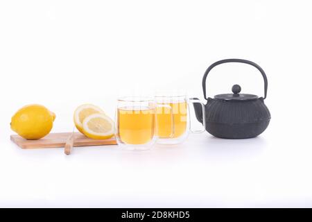 tè verde in due tazze trasparenti con teiera nera e limone isolato su sfondo bianco Foto Stock