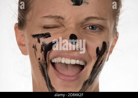 Felice bellissima ragazza con acne sorridente su sfondo bianco in un cosmetico nero maschera Foto Stock