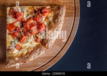 Una fetta di pizza con peperoni dolci si trova su un tagliere di legno su uno sfondo scuro.quattro diversi sapori di pizza. Spazio per il testo. La vista da Th Foto Stock