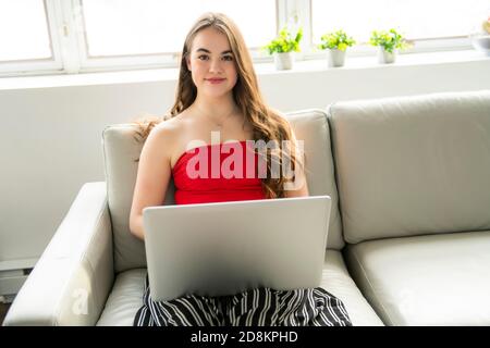 Una ragazza teenager seduta in divano che naviga su internet Foto Stock