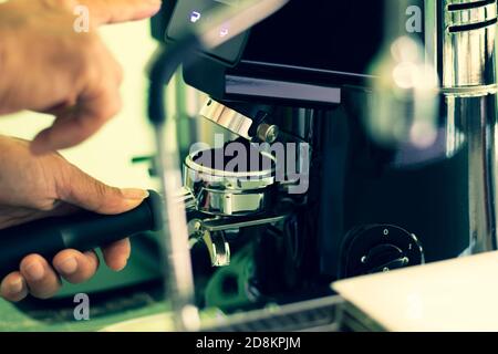 Barista macina a mano il caffè speciale appena tostato in una macchina professionale. Foto Stock