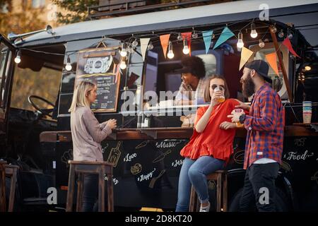 persone che socializzano di fronte al cibo per camion, bere succhi di frutta Foto Stock