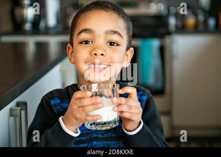 Carino afroamericano ragazzo che beve latte a casa Foto Stock