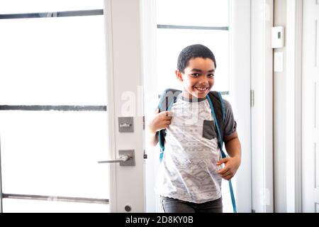 Un bambino che viene a casa passando attraverso la porta dopo scuola Foto Stock