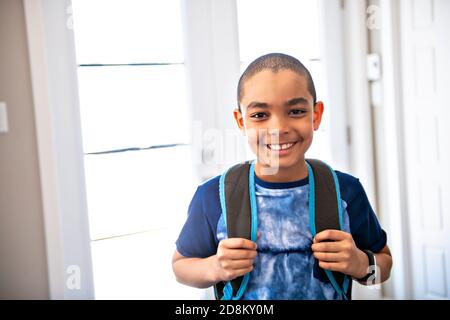 Un bambino che viene a casa passando attraverso la porta dopo scuola Foto Stock