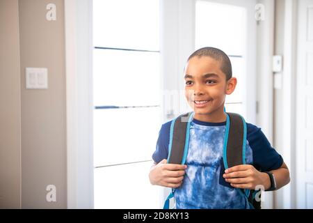 Un bambino che viene a casa passando attraverso la porta dopo scuola Foto Stock