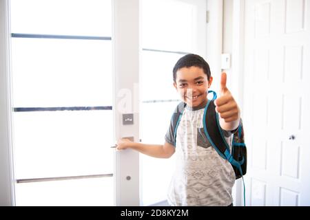 Un bambino che viene a casa passando attraverso la porta dopo scuola Foto Stock