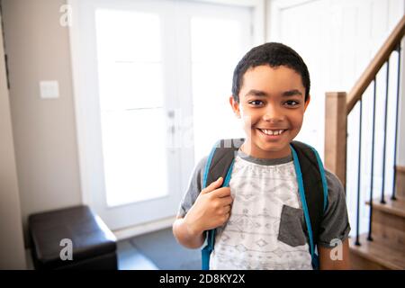 Un bambino che viene a casa passando attraverso la porta dopo scuola Foto Stock