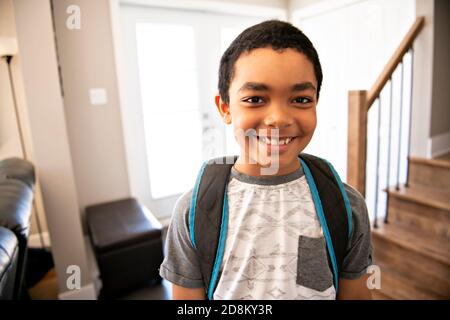 Un bambino che viene a casa passando attraverso la porta dopo scuola Foto Stock