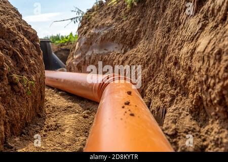 costruzione di un drenaggio dell'acqua piovana al contenitore di raccolta con l'ausilio di un tubo di plastica Foto Stock