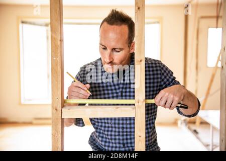 Un uomo che lavora nel locale di lavoro del falegname con nastro adesivo Foto Stock