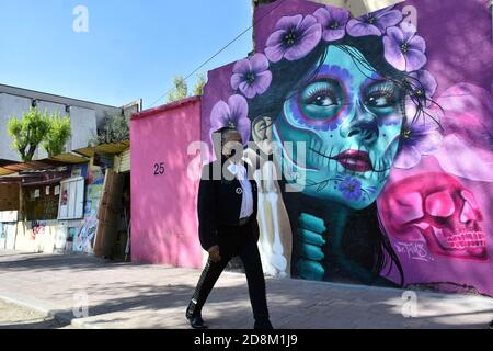 Città del Messico, Messico. 30 Ott 2020. CITTÀ DEL MESSICO, MESSICO - 30 OTTOBRE: Un Mariachi cammina davanti a un graffito che rappresenta il giorno del Messico delle tradizioni morte per commemorare le vittime che hanno perso la vita a causa della malattia di Covid-19 il 30 ottobre 2020 a Città del Messico, Messico. Credit: Carlos Tischler/Eyepix Group/The Photo Access Credit: The Photo Access/Alamy Live News Foto Stock