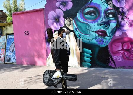 Città del Messico, Messico. 30 Ott 2020. CITTÀ DEL MESSICO, MESSICO - 30 OTTOBRE: Un Mariachi cammina davanti a un graffito che rappresenta il giorno del Messico delle tradizioni morte per commemorare le vittime che hanno perso la vita a causa della malattia di Covid-19 il 30 ottobre 2020 a Città del Messico, Messico. Credit: Carlos Tischler/Eyepix Group/The Photo Access Credit: The Photo Access/Alamy Live News Foto Stock